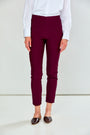 A model wearing high-waisted, cropped burgundy pants, paired with a white long-sleeve blouse and brown pointed-toe flats, shown from the waist down against a plain white studio background.