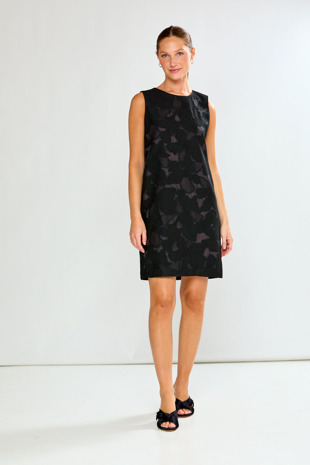 Woman wearing a black dress with a subtle pattern on a white background