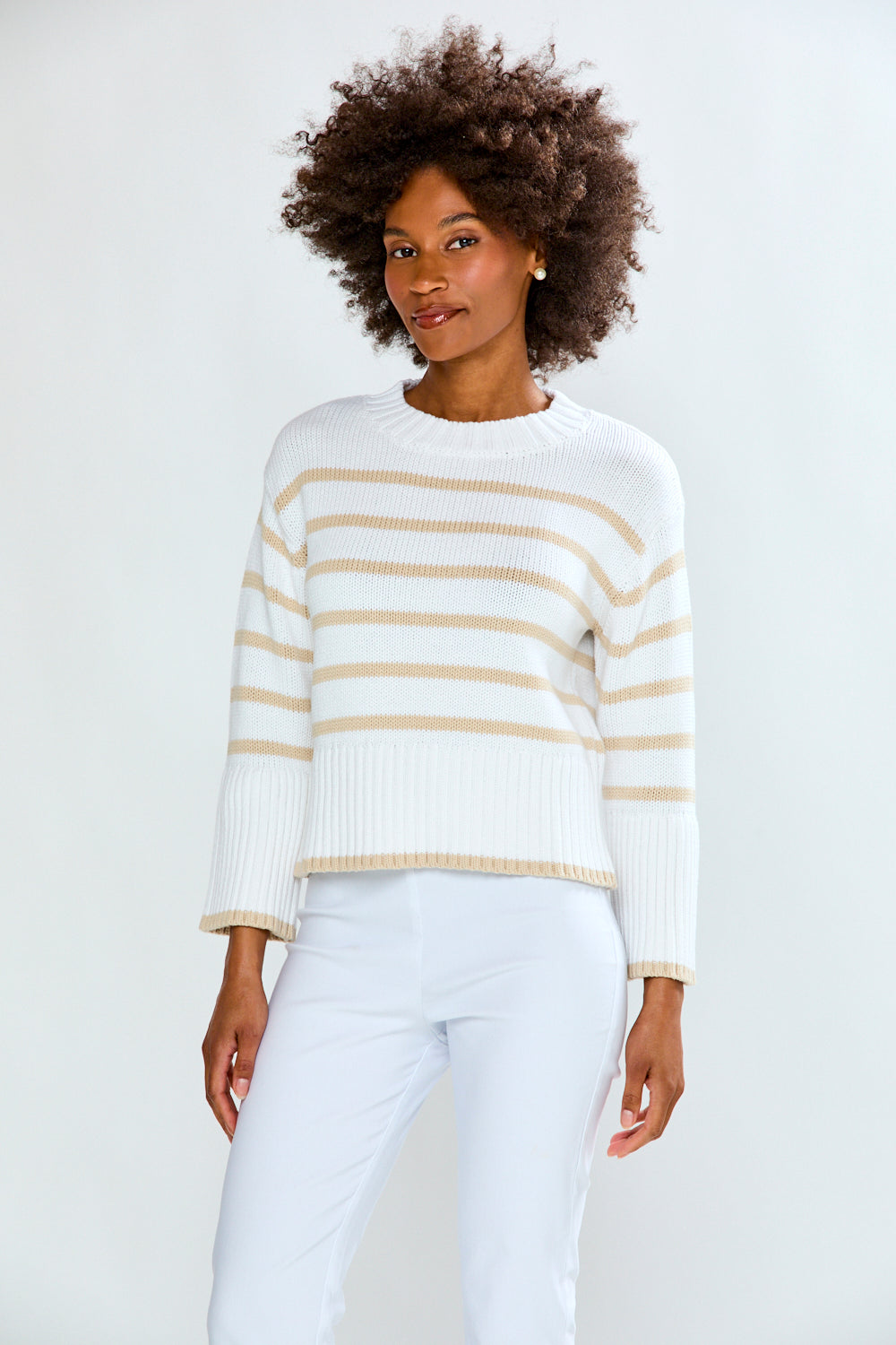 Woman wearing a white sweater with gold stripes against a plain background