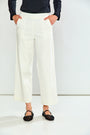 A person wearing off-white cropped wide-leg pants with a black long-sleeve top and black flat shoes, standing against a plain white studio background.