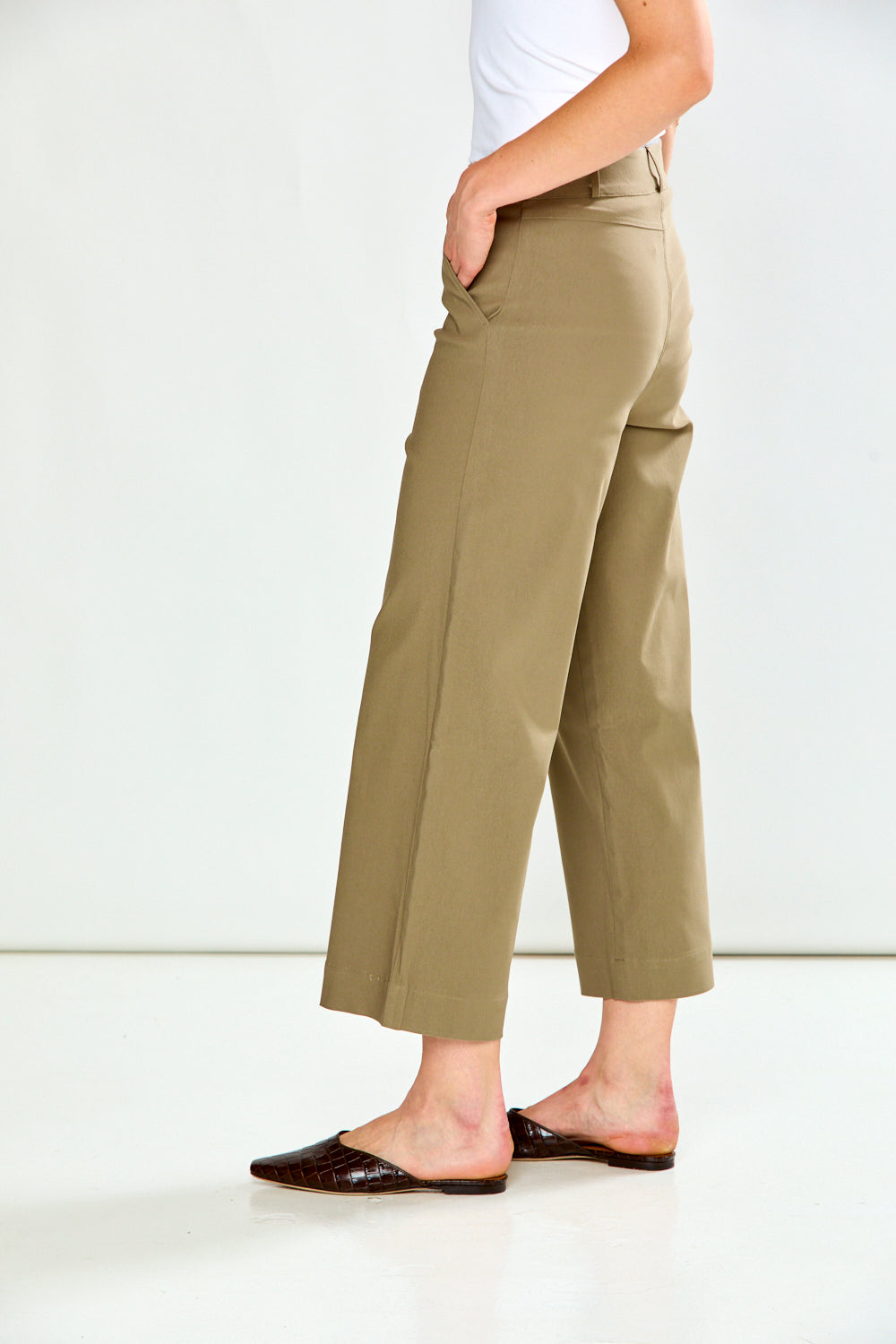 A model wearing a pair of mushroom cropped wide-leg trousers, paired with a white top and dark brown flat shoes, against a plain white studio background.
