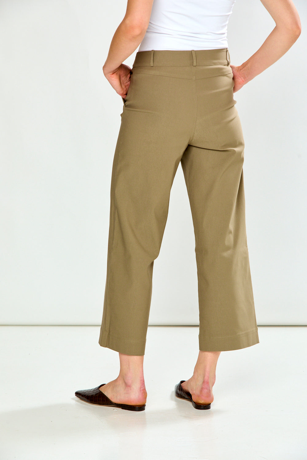 A model wearing a pair of mushroom cropped wide-leg trousers, paired with a white top and dark brown flat shoes, against a plain white studio background.