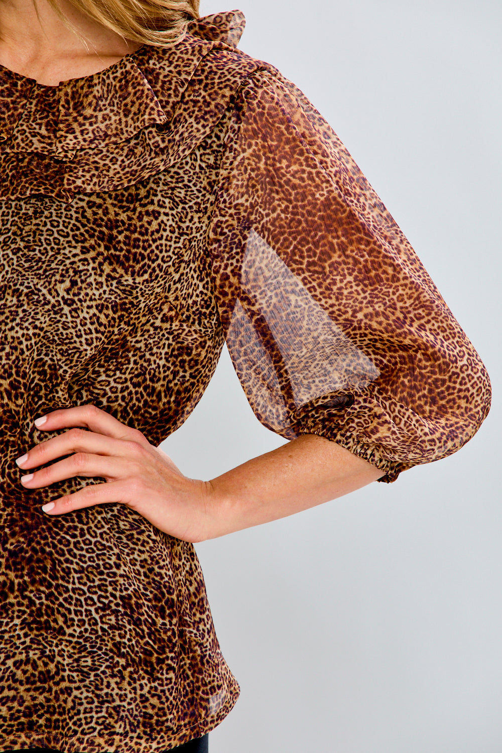 Leopard print blouse with sheer sleeves on a plain background