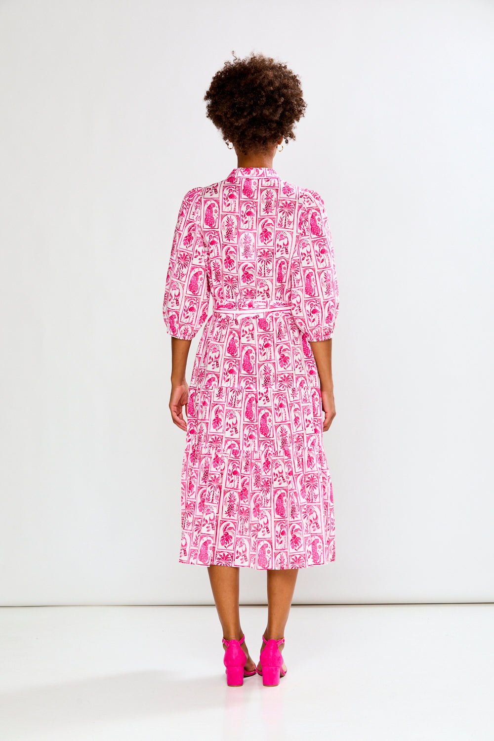 Woman wearing a pink and white patterned dress on a white background