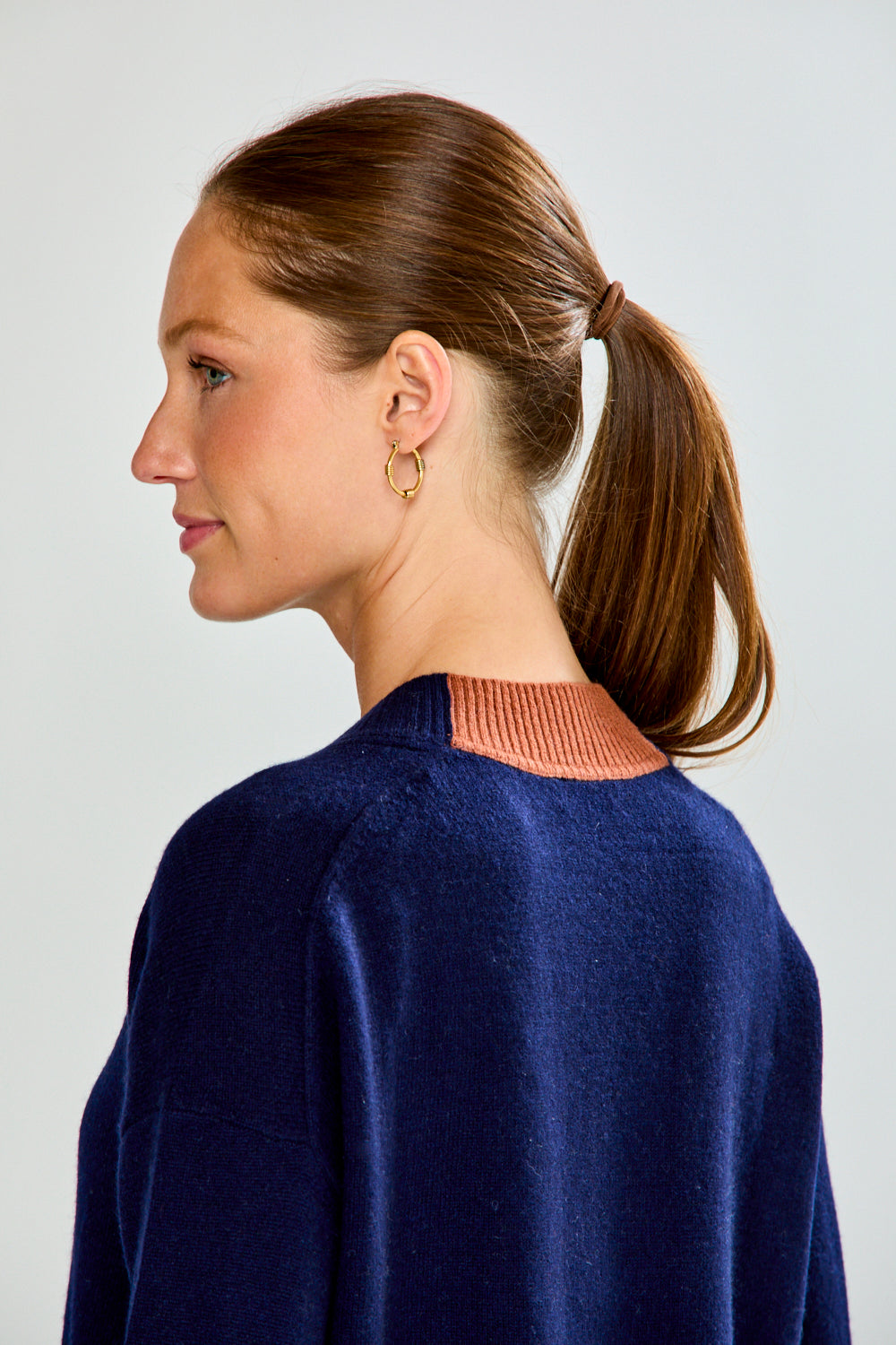 Woman wearing a navy sweater and blue jeans against a plain background