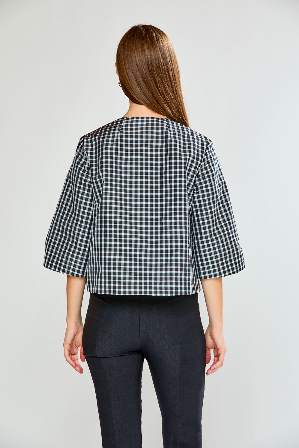 Person wearing a black and white checkered top with a plain background
