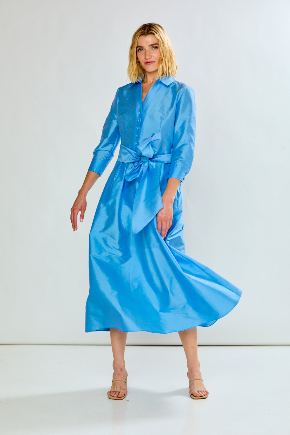 The Ainsley Dress - Light Blue, a sophisticated long sleeve shirt dress with button front, tied waist, flowing skirt, and vibrant blue finish.