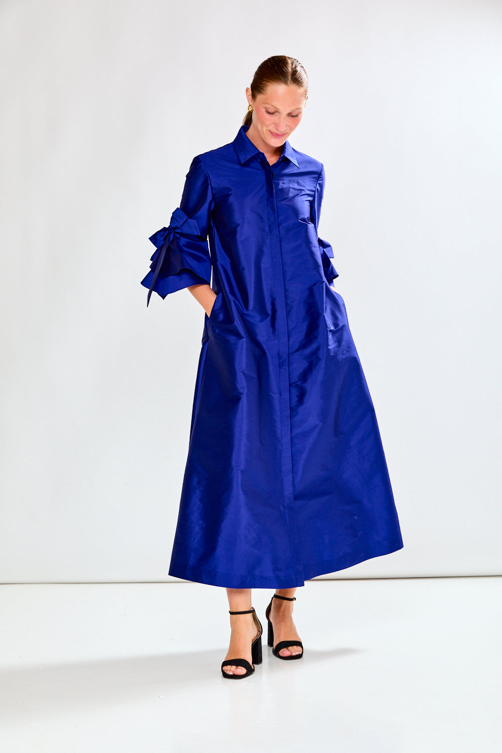 Woman wearing a long blue dress against a white background