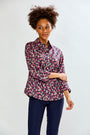 Woman wearing a floral shirt and dark pants on a white background