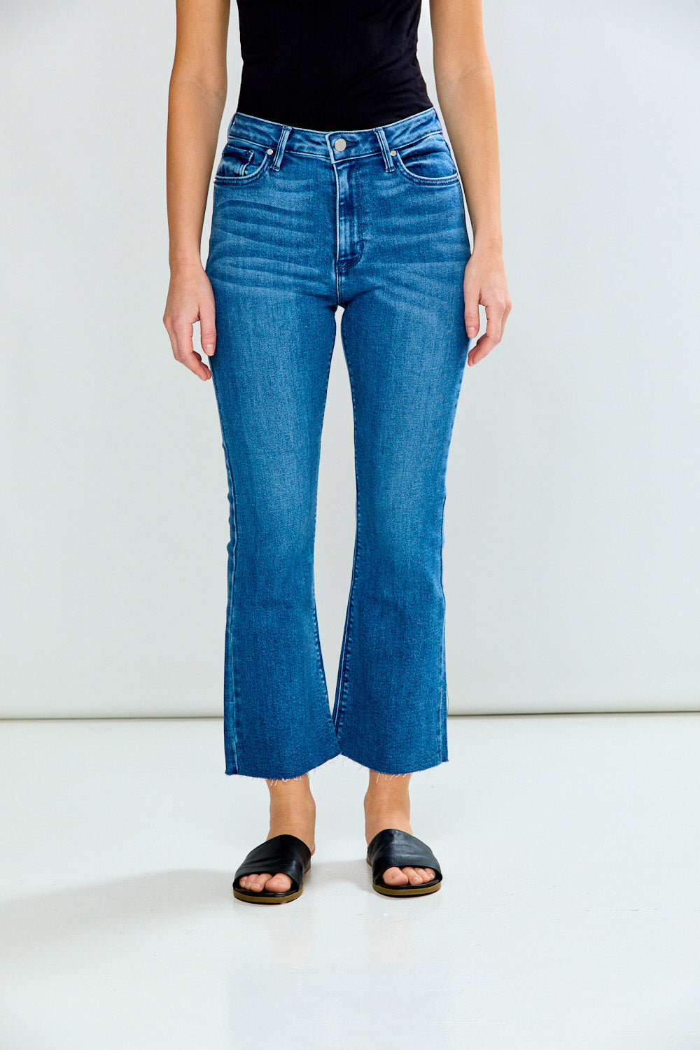 Person wearing blue jeans and a black top on a white background