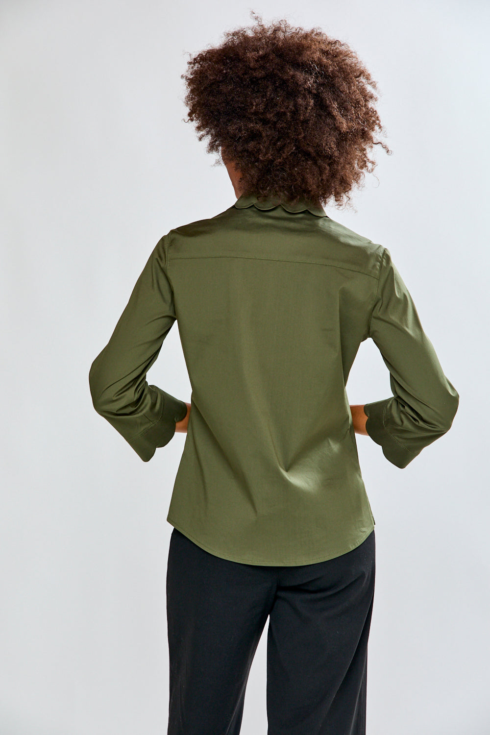 Person wearing an olive green jacket on a white background