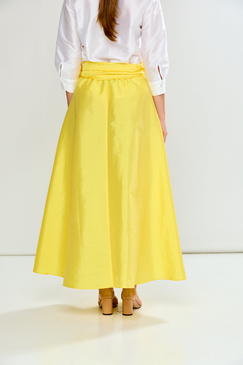 Person wearing a white shirt and yellow skirt on a white background