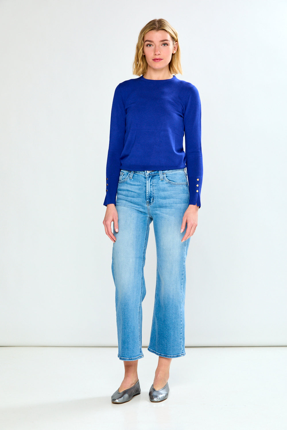 Woman wearing a blue sweater and light blue jeans on a white background