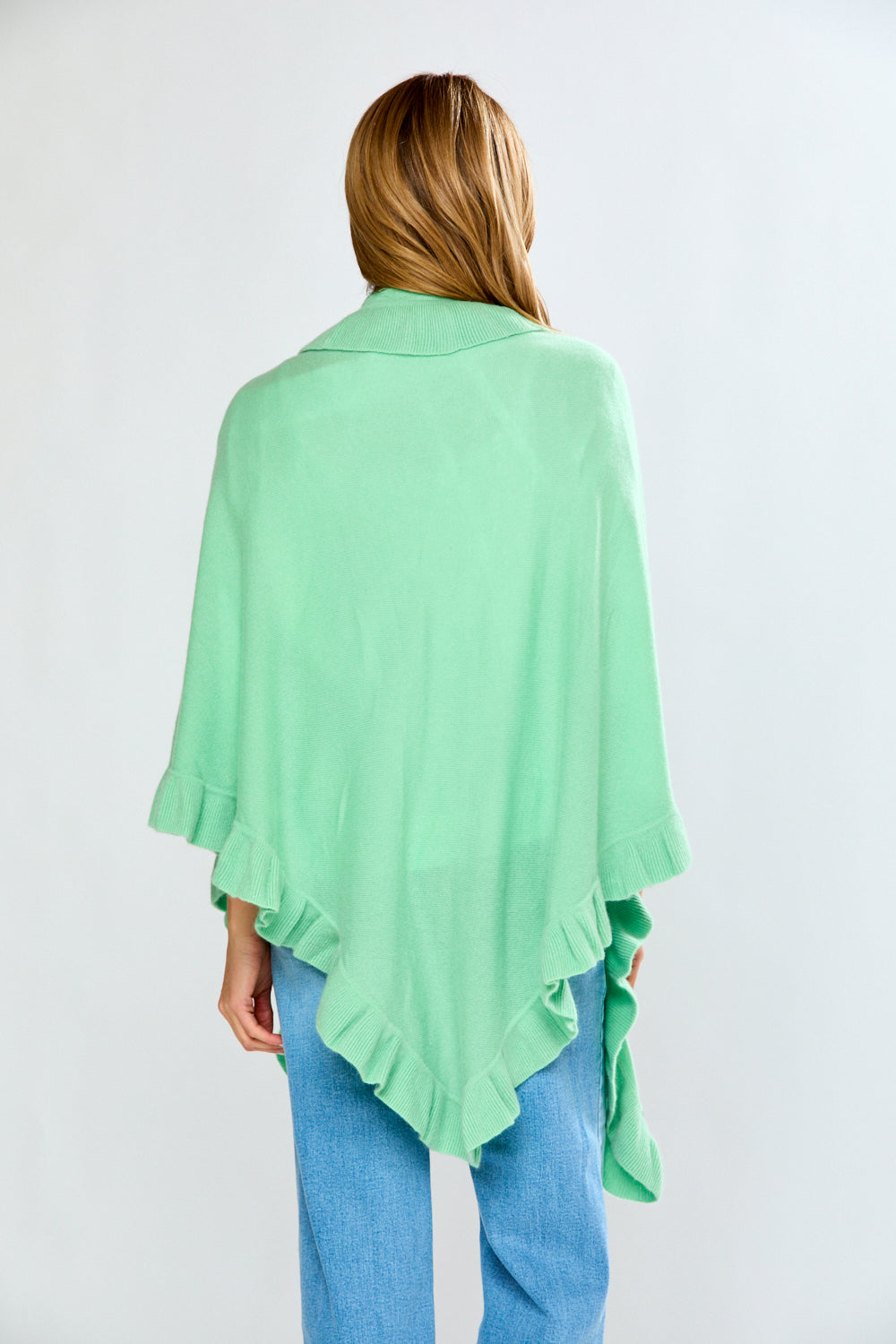 Person wearing a light green poncho with a plain background