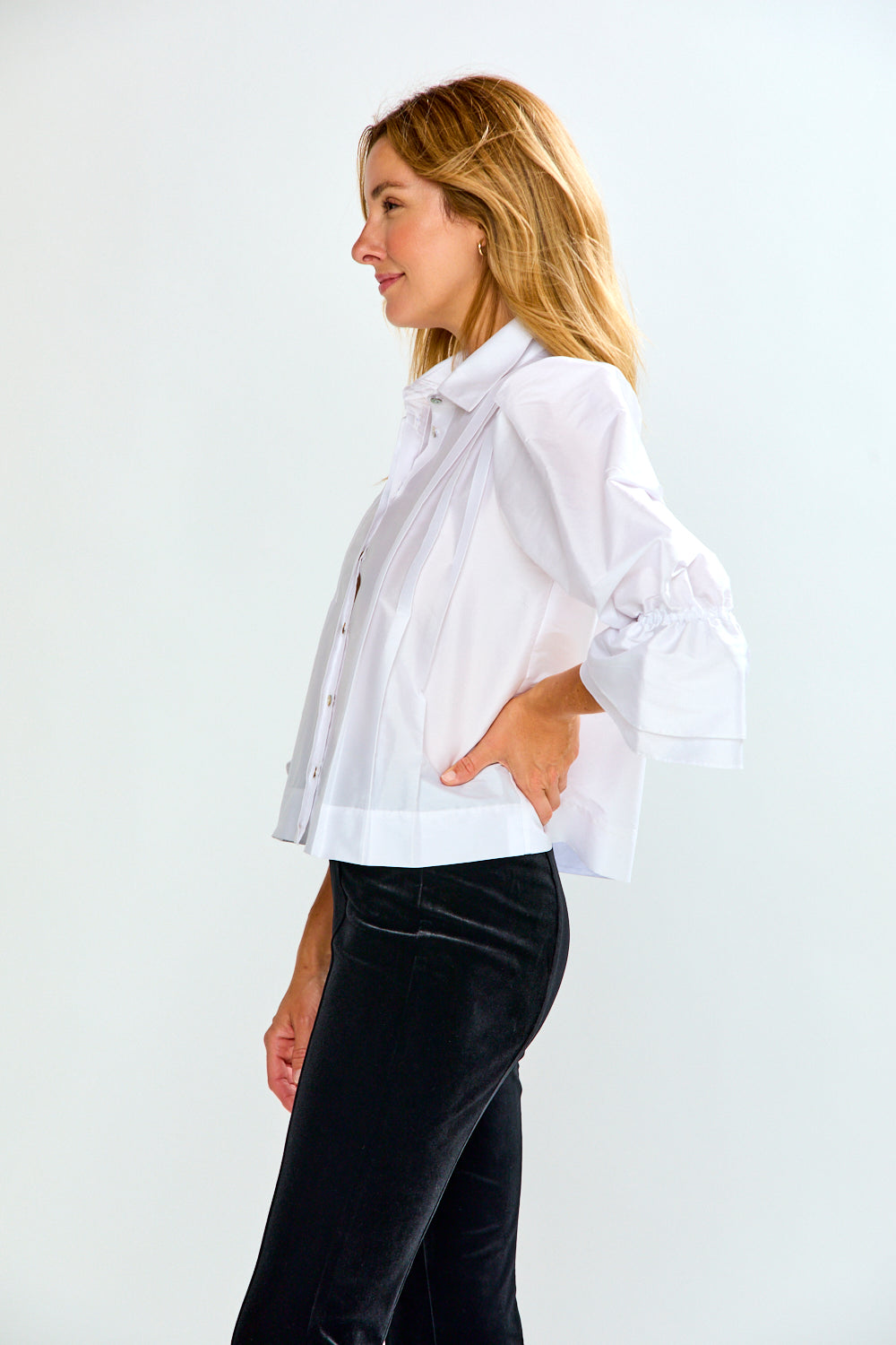 The Arlo Top in Taffeta - White, a white blouse with a tie neck and gathered puff sleeves, modeled with black pants in side profile