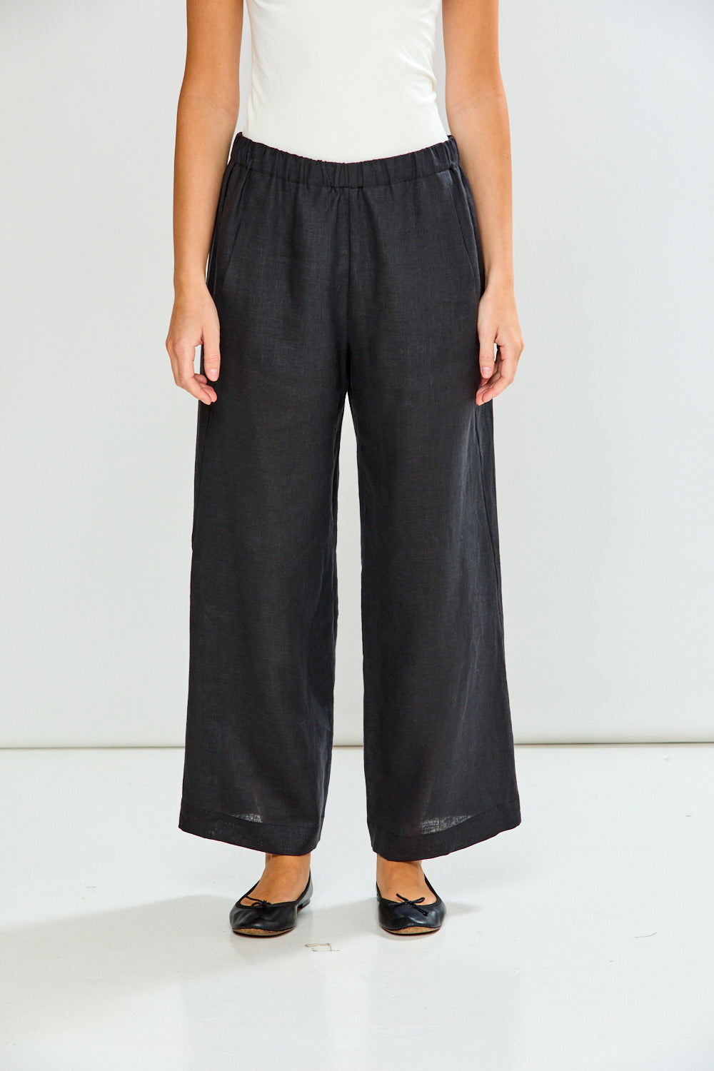 Person wearing black wide-leg pants on a white background