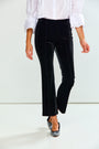 A model wearing black velvet high-waisted cropped flare pants, paired with a white blouse and black pointed flats, shown from the waist down against a white studio background.