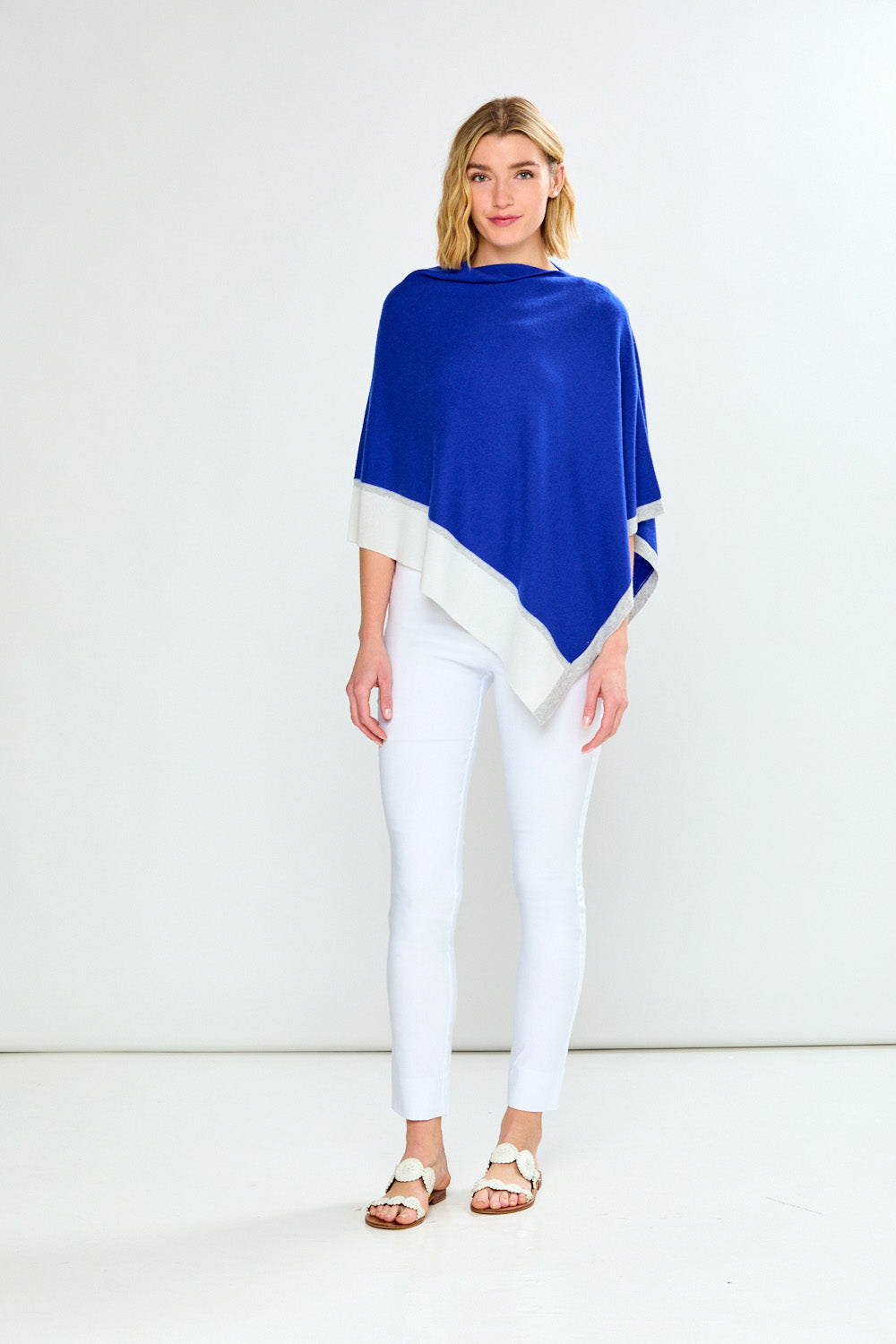 Woman wearing a blue and white poncho against a white background
