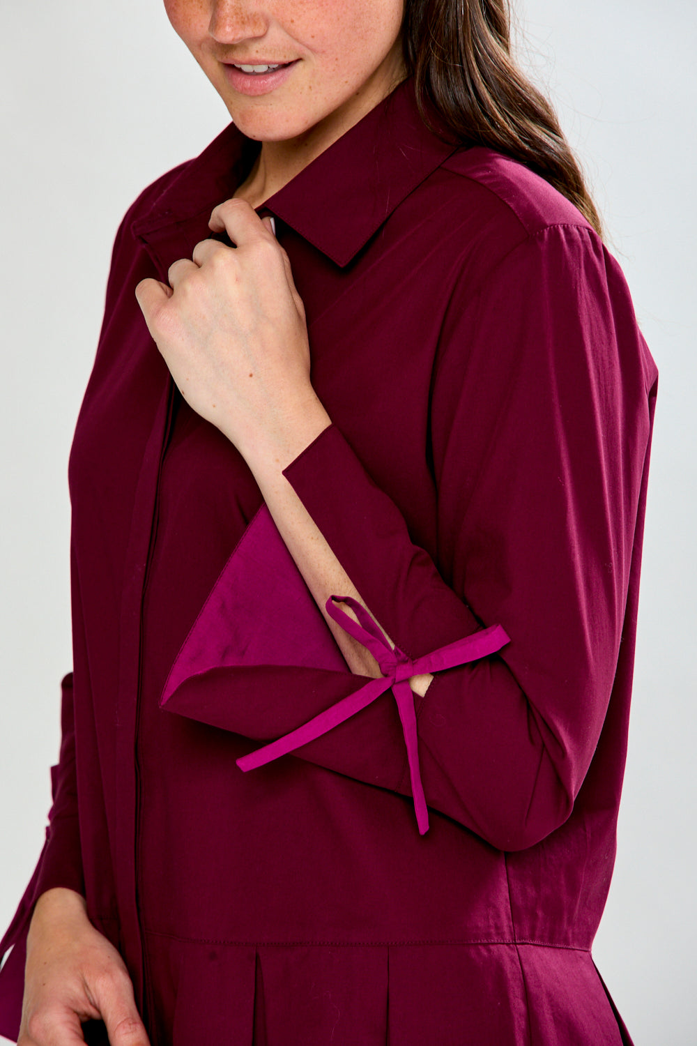 Woman wearing a raisin dress with long sleeves on a white background