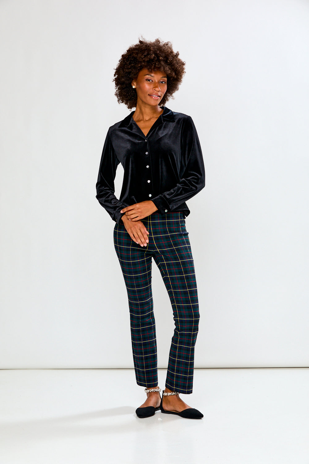 Woman wearing a black satin shirt and plaid pants on a white background
