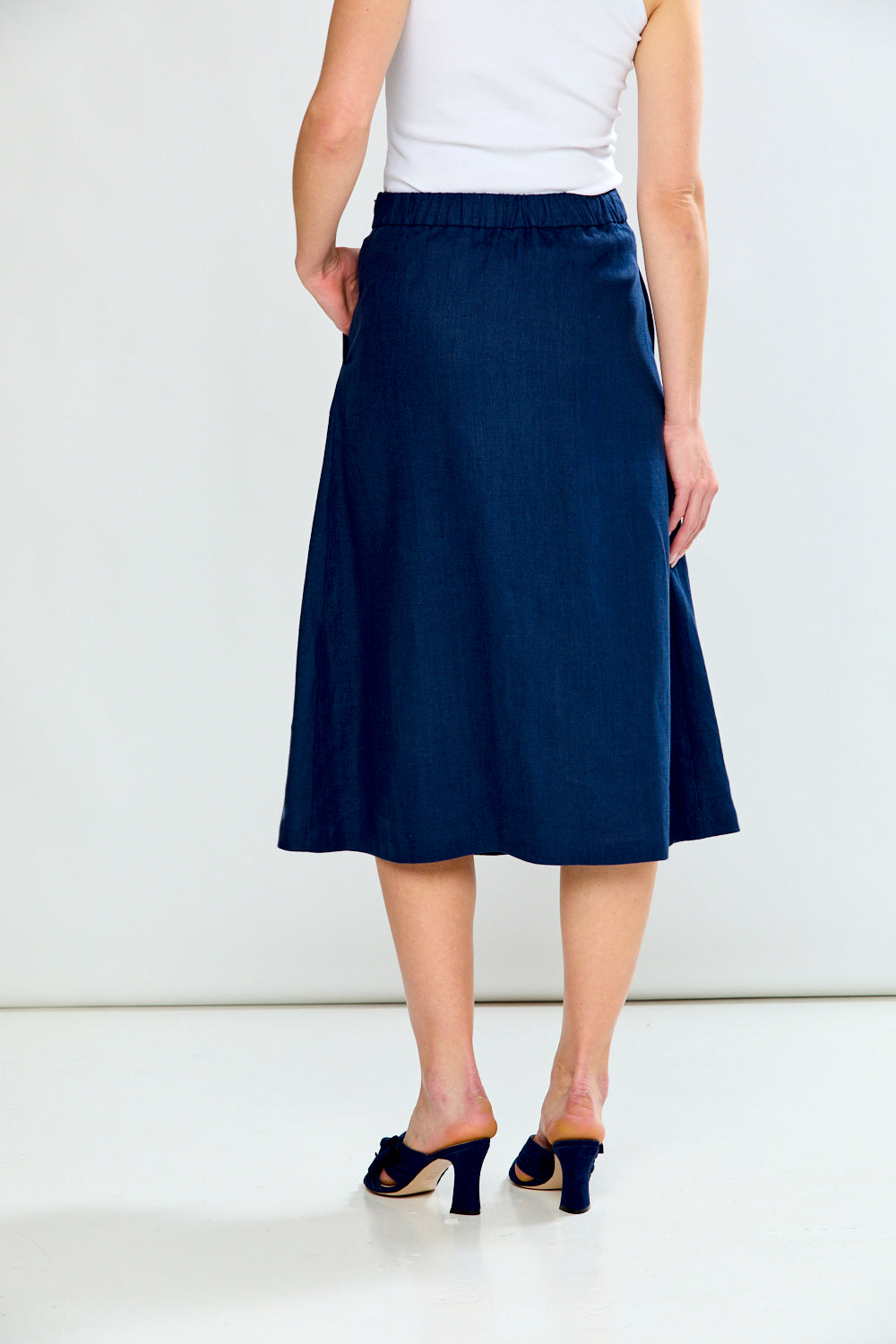Person wearing a navy blue skirt with a white top on a white background
