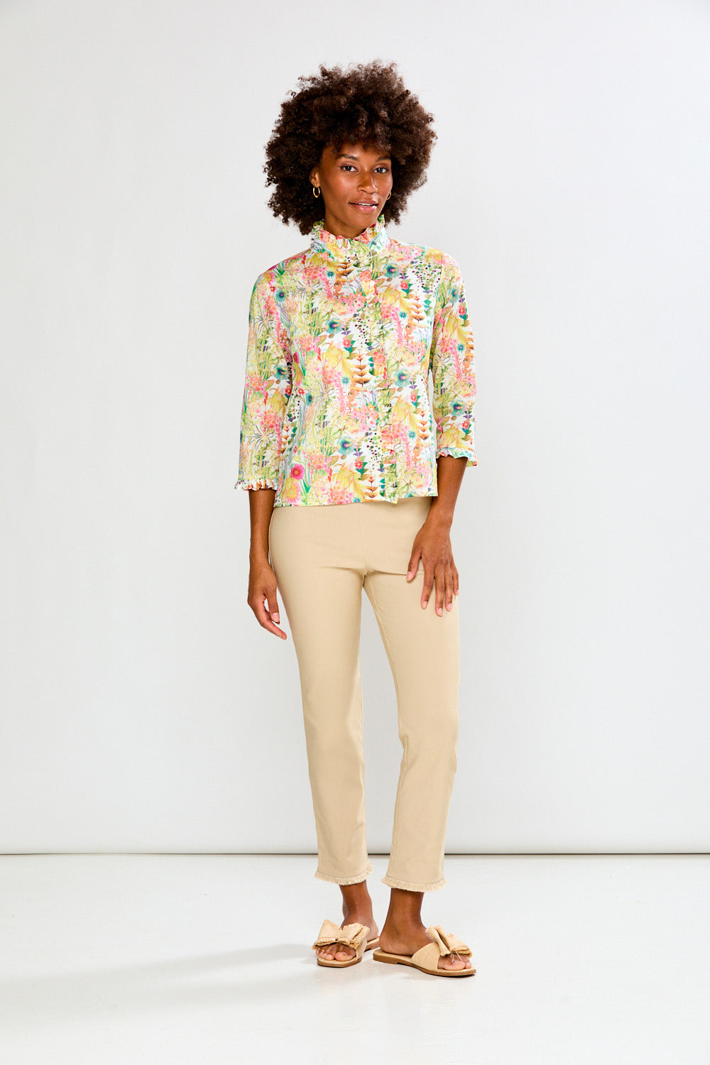 Woman wearing a floral blouse and beige pants on a white background