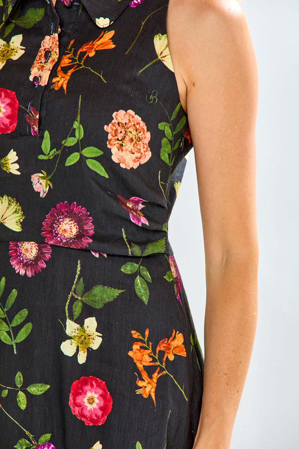 Woman wearing a black linen dress with multi colored flowers on it