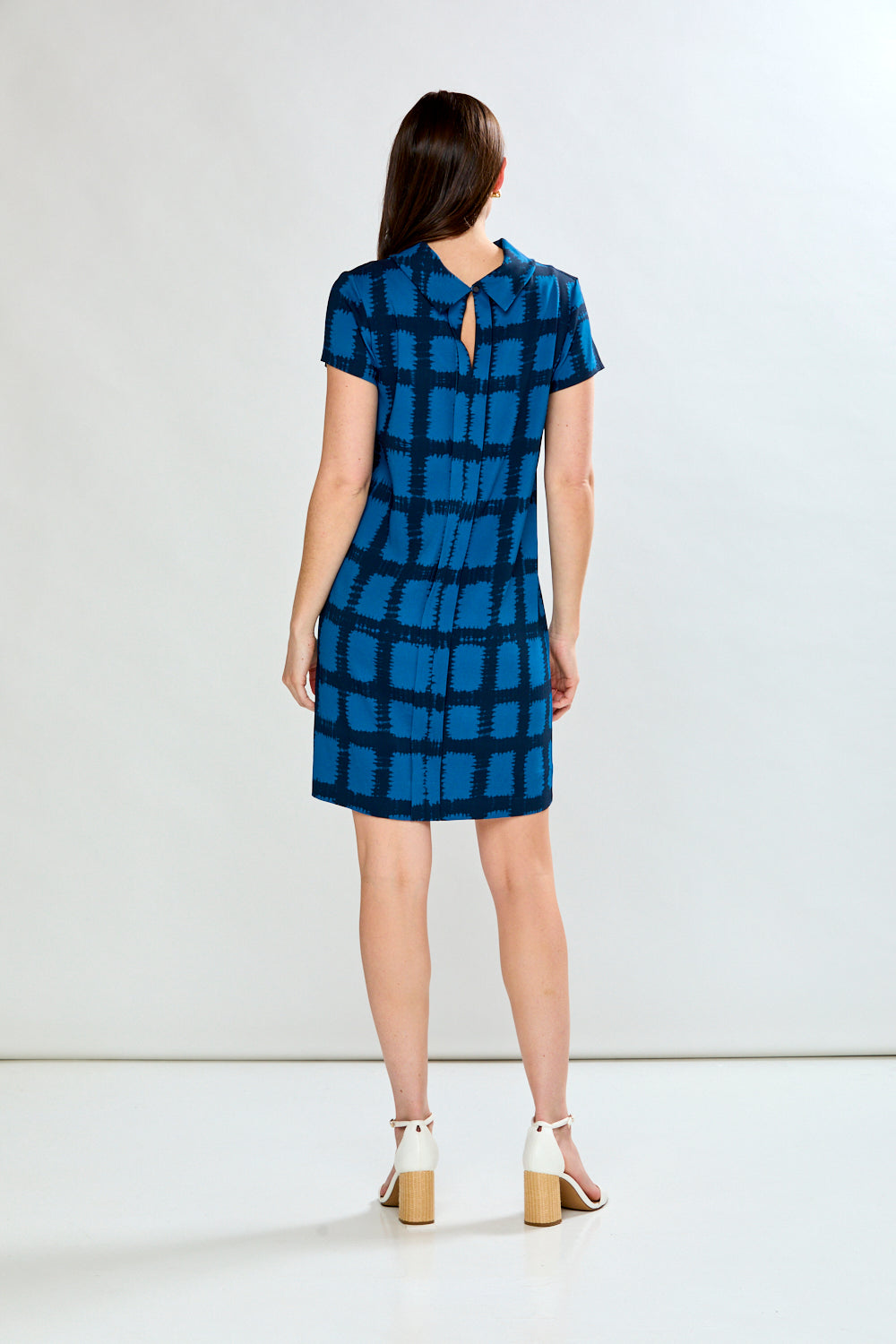 Woman wearing a blue checkered dress against a white background