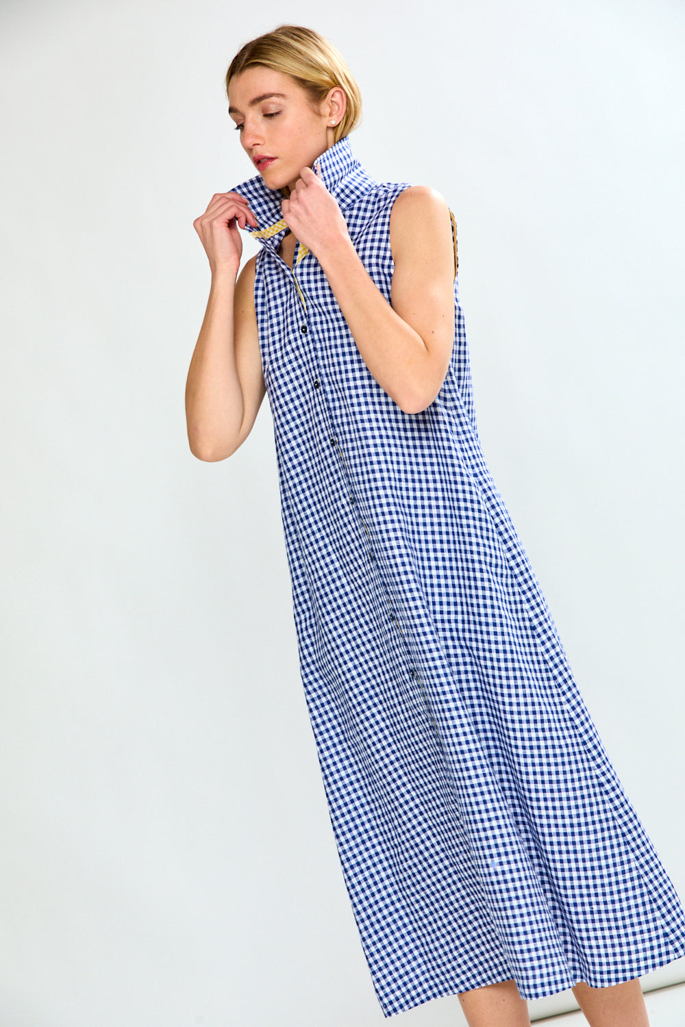 Woman wearing a blue and white checkered dress against a plain background