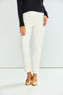 A model from the waist down wearing off-white cropped trousers, a black long-sleeve top, and metallic gold flats, standing against a plain white studio background.