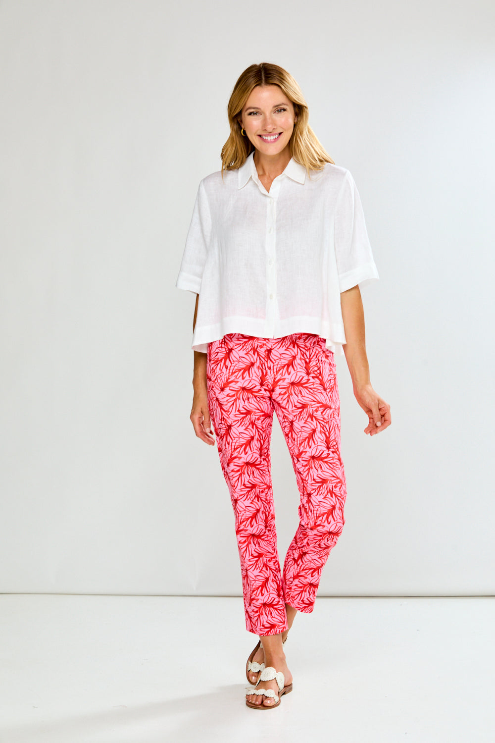 Woman wearing a white shirt and pink patterned pants on a white background