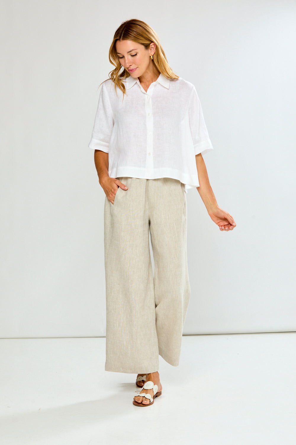 Woman wearing a white shirt and beige pants on a white background