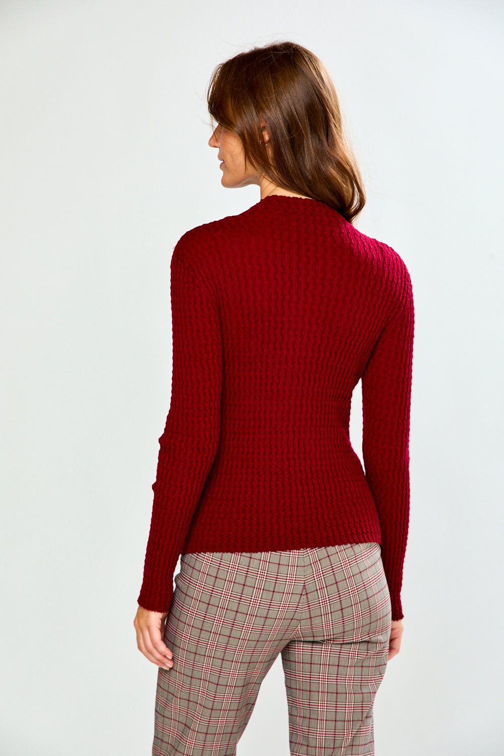 The Texture Long Sleeve in Aubergine featuring a fitted textured knit design and long sleeves styled with plaid pants for a chic sophisticated look