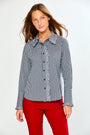 A woman modeling a long-sleeve button-up shirt with a black and white gingham pattern and a solid gray ruffled collar and placket, paired with red pants, against a plain white studio background.