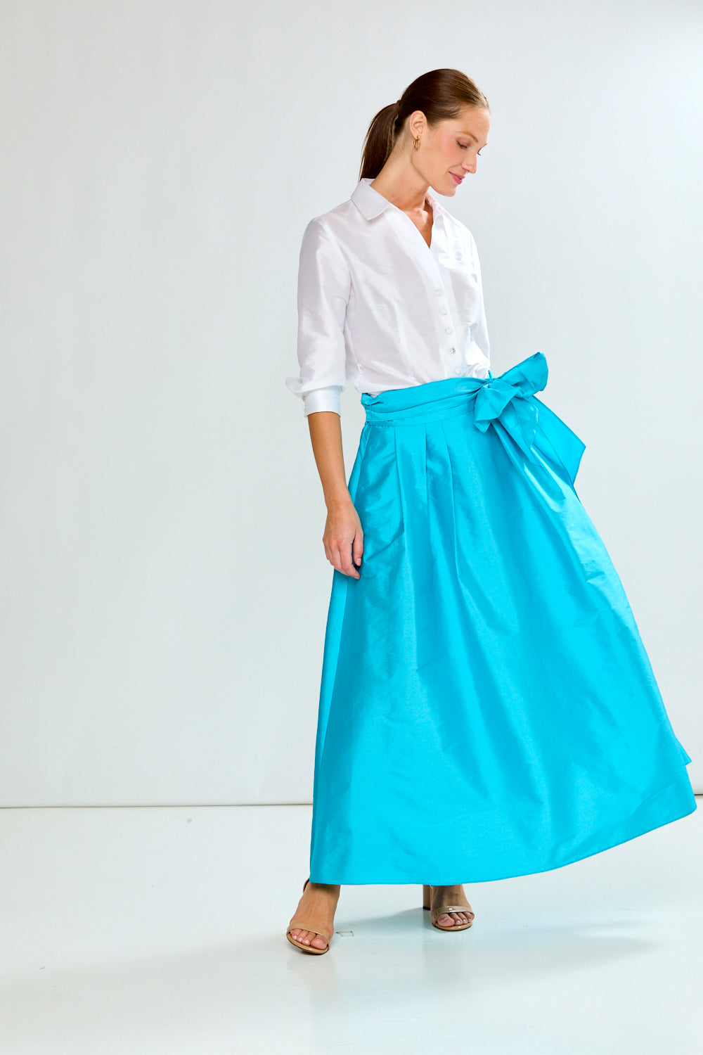 Woman wearing a white shirt and blue skirt on a white background