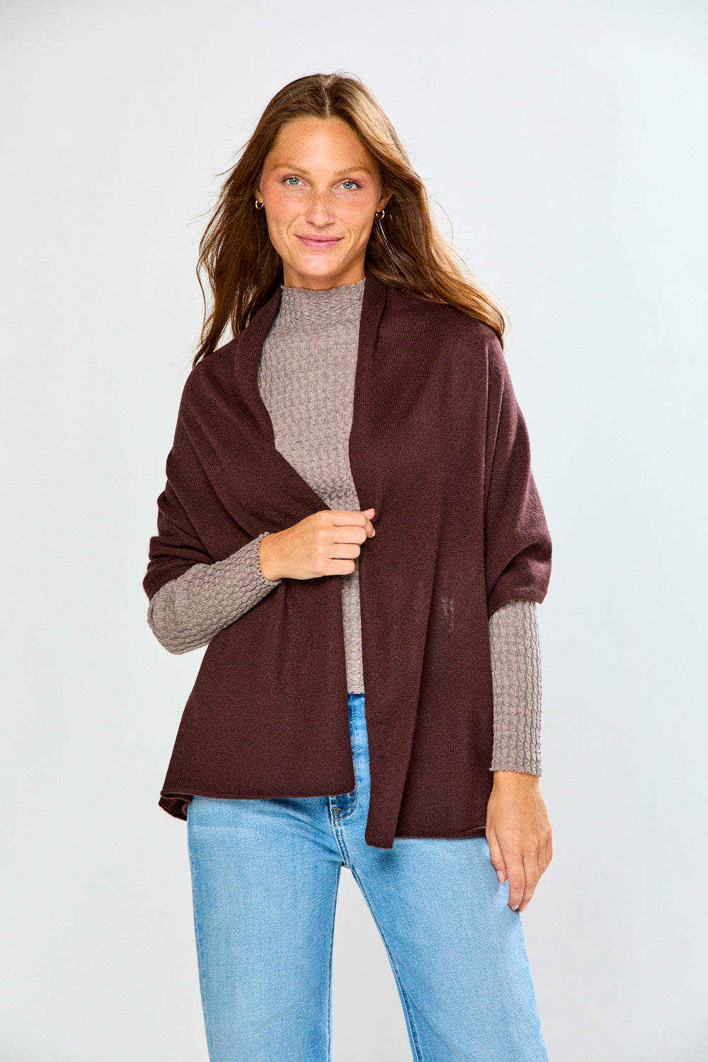 The Classic Cashmere Scarf in burgundy draped over a woman wearing a taupe sweater and jeans for a sophisticated timeless look with women's accessories