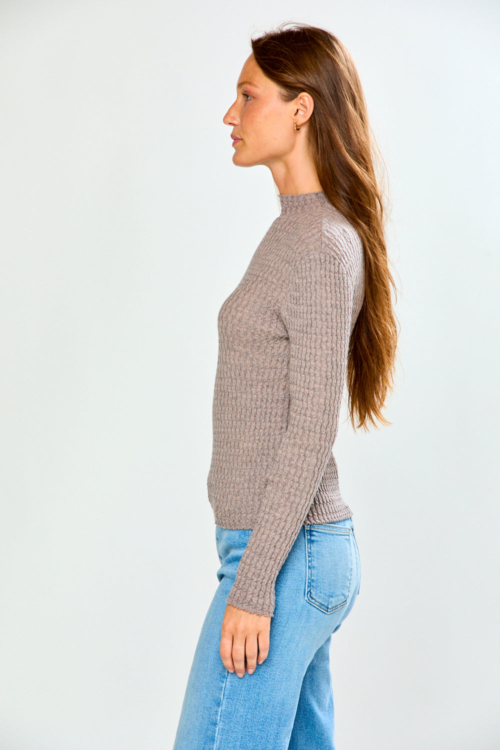 The Texture Long Sleeve in Heather Taupe worn with light wash jeans in side profile. Textured wool and cashmere knit sweater with timeless style