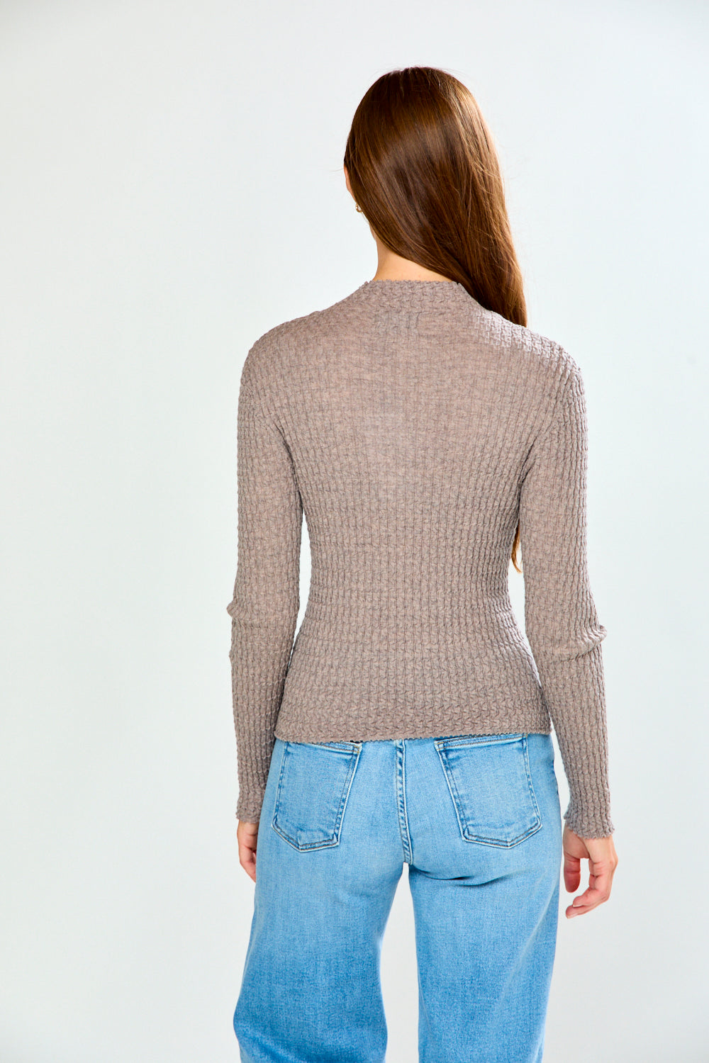 The Texture Long Sleeve in Heather Taupe shown from the back on a model with blue jeans showcasing its textured knit and fitted silhouette