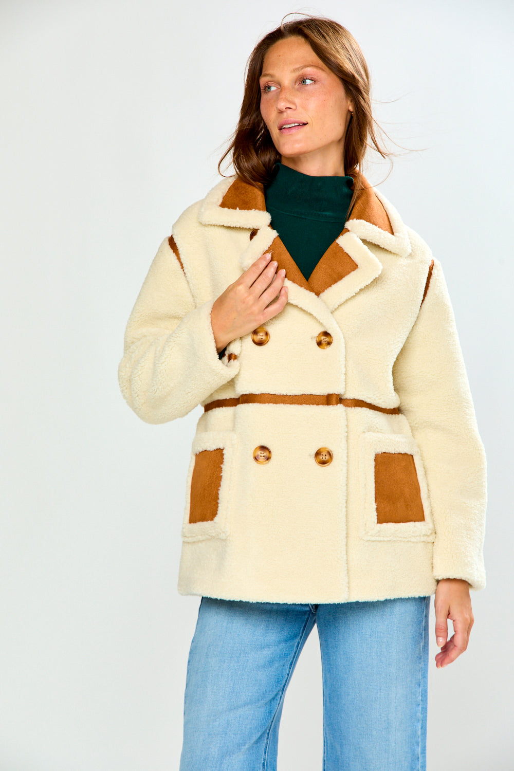 Model wearing The Phoenix Coat - Tan a chic shearling style women's jacket with tan trim and patch pockets over jeans