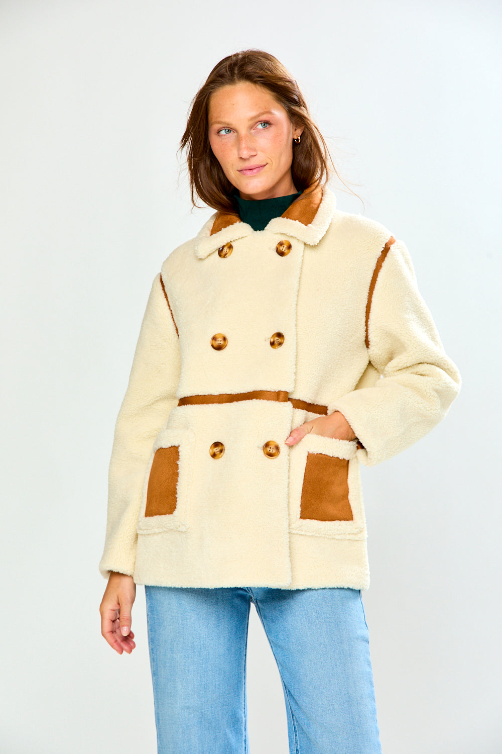 The Phoenix Coat - Tan shown on a woman in a cozy shearling style coat with contrast trim and patch pockets paired with jeans for a chic classic look