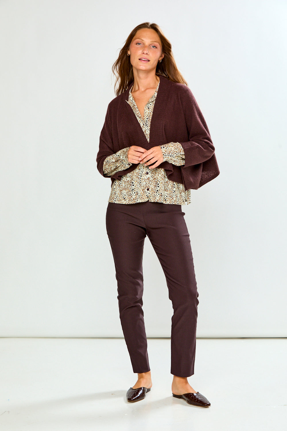 The Shrug with Kimono Sleeves in Toffee in 100% cashmere styled over a floral blouse with tailored pants and flats for a chic sophisticated look