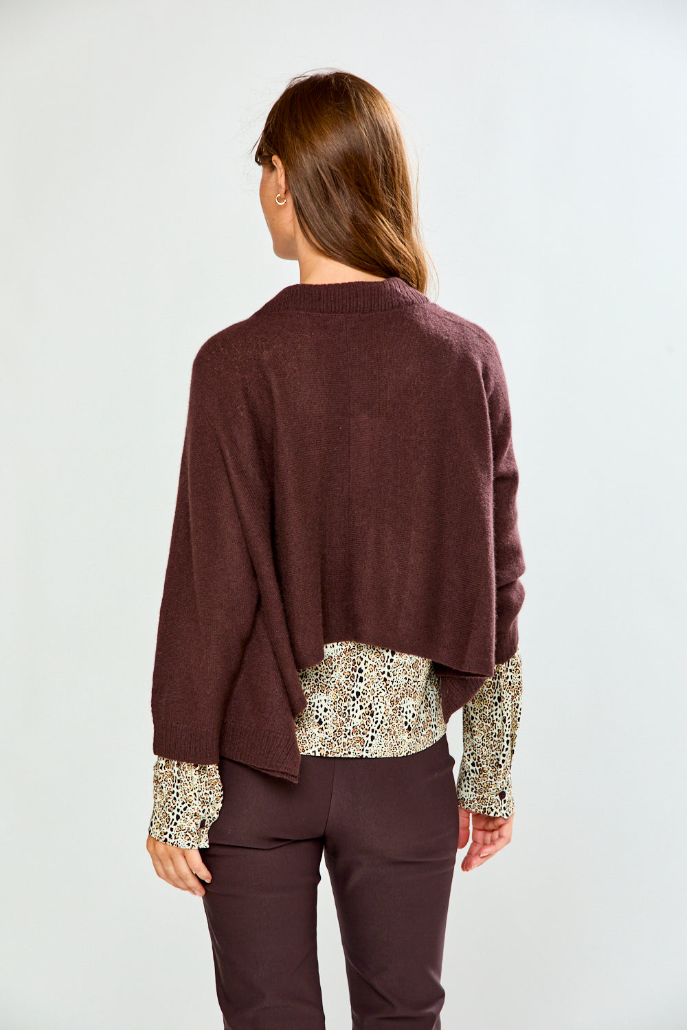The Shrug with Kimono Sleeves in Toffee shown from the back on a model with a relaxed draped fit over a patterned blouse in a chic women's sweater style