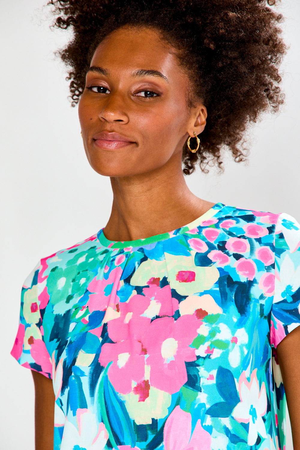 Woman wearing a colorful floral dress against a white background