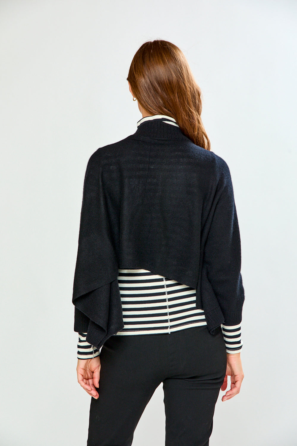 The Shrug with Kimono Sleeves in Black shown from the back over a striped top with black pants in a chic womens sweaters look