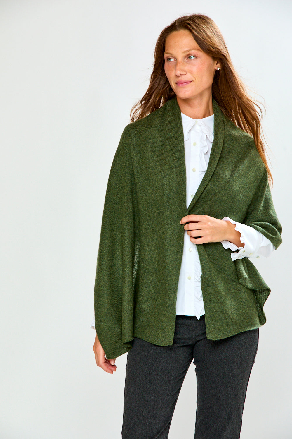 The Classic Cashmere Scarf in 100% cashmere draped as a forest green wrap over a white blouse and dark pants for a sophisticated timeless look