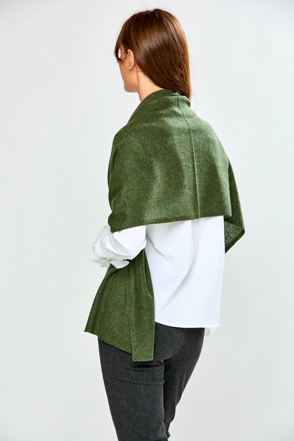 The Classic Cashmere Scarf in green draped over a woman wearing a white blouse and dark jeans for a sophisticated timeless fashion look