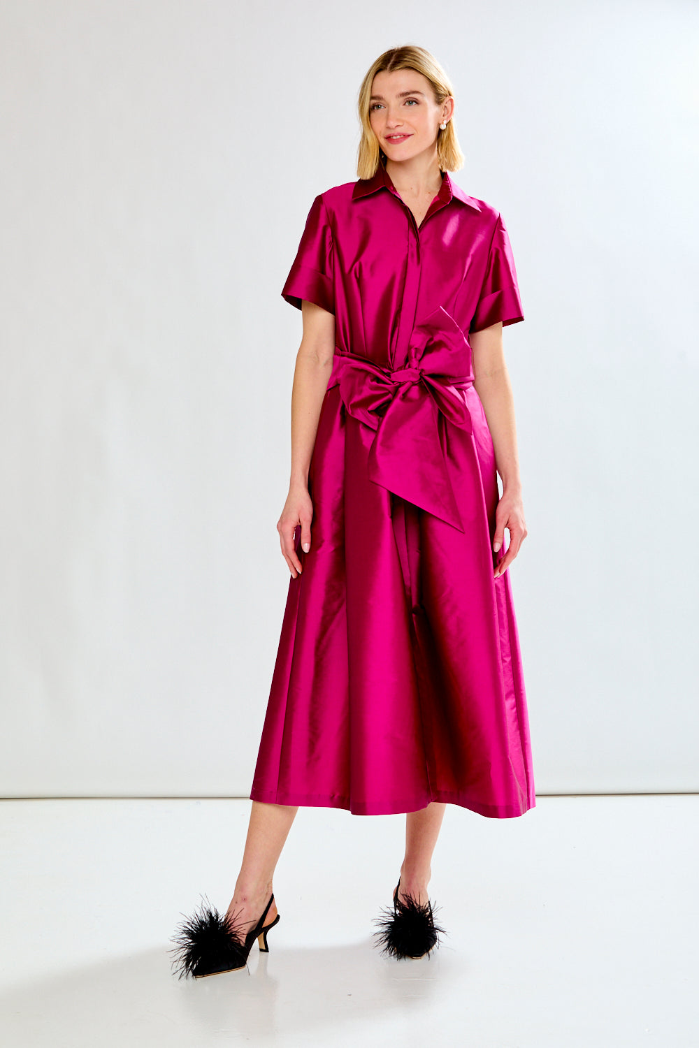 Woman wearing a bright pink satin dress with a white background