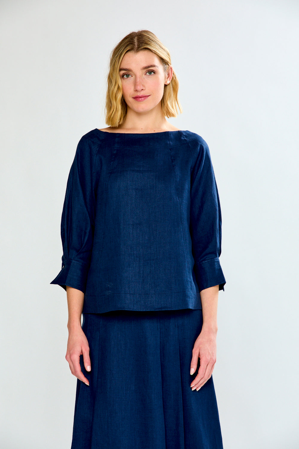 Woman wearing a navy blue top and skirt set against a white background