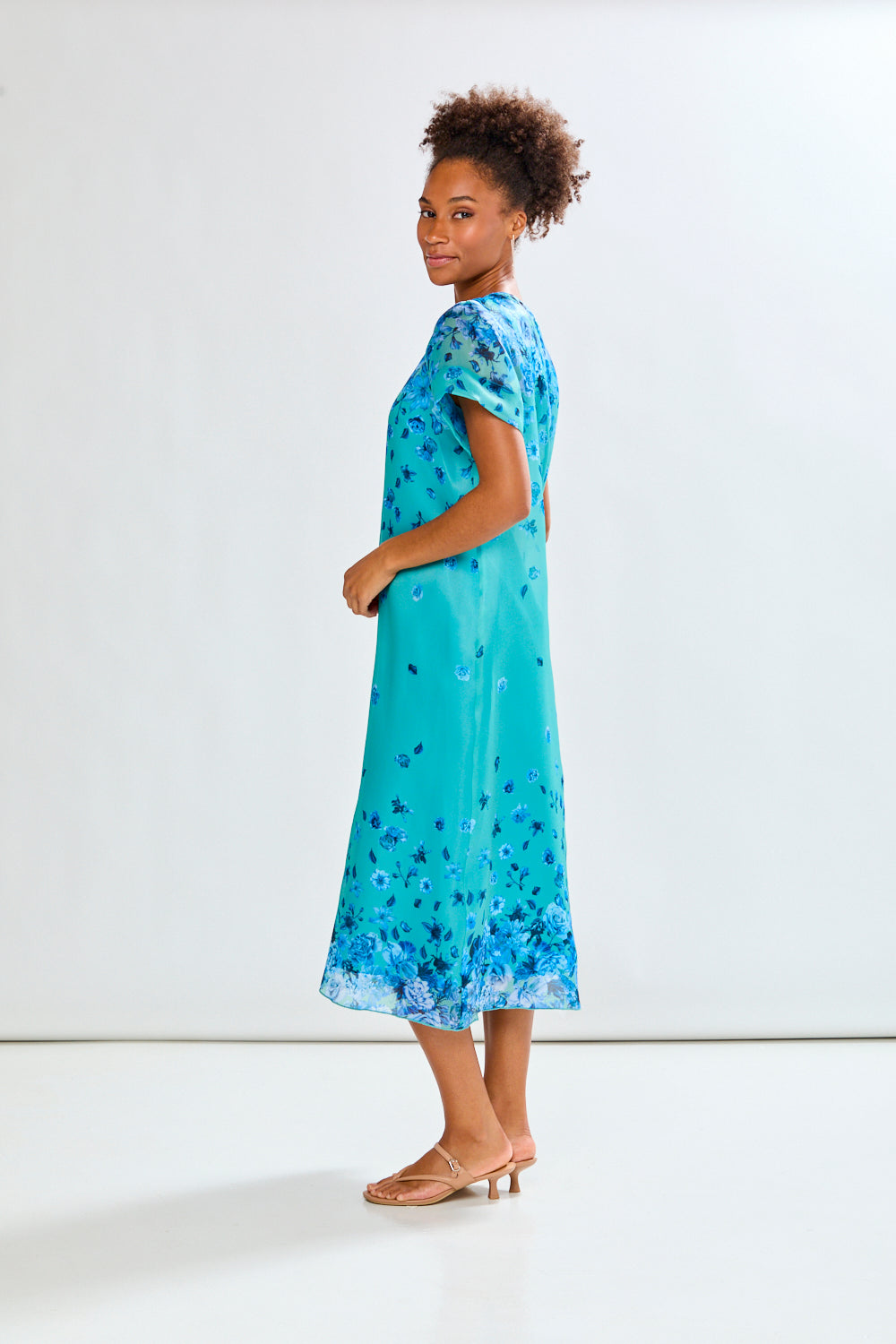 Woman wearing a blue floral dress against a white background