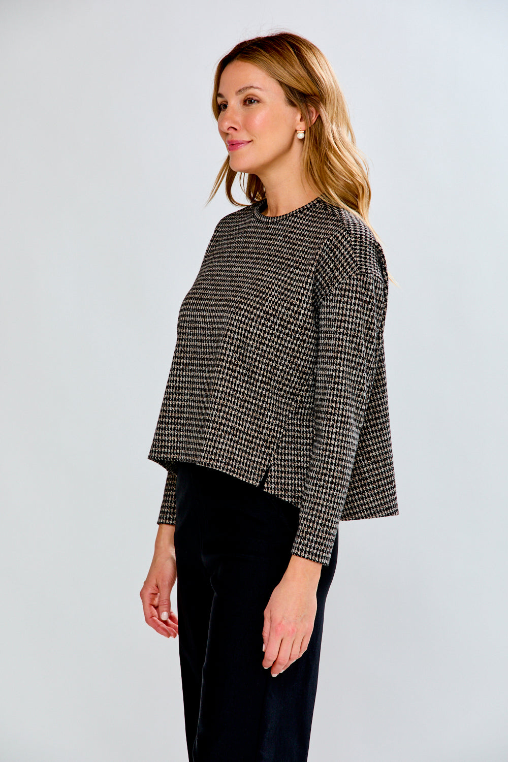 Woman wearing a plaid top with black pants on a light gray background